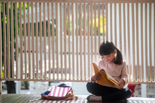 Cute Asian Girl Reading a Book at Home