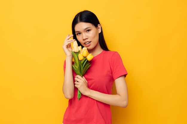 花の花束と赤いTシャツのかわいいアジアの女の子