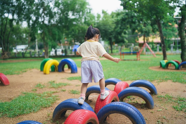 Sorriso ragazza asiatica carina gioca a scuola o nel cortile dell'asilo o nel parco giochi attività estiva sana per i bambini piccola ragazza asiatica che si arrampica all'aperto nel parco giochi bambino che gioca nel parco giochi all'aperto
