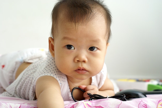 Симпатичный азиатский ребенок младенца, лежащий на полу в комнате