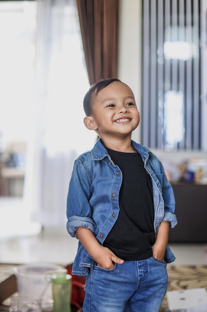 Cute Asian little boy in denim casual style is standing confidently and smiling to the camera.