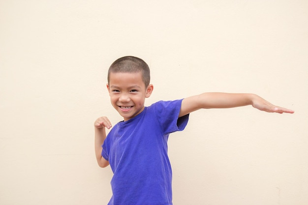 Photo cute asian little boy smiling happily and standing in the studio room with wall background