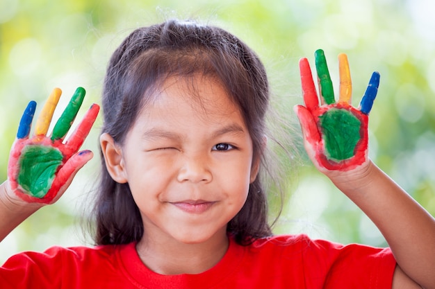 Cute asian little child girl with painted hands smiling with fun and happiness