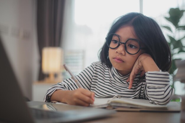 Cute Asian little girl children using a laptop computer studying through an online elearning system