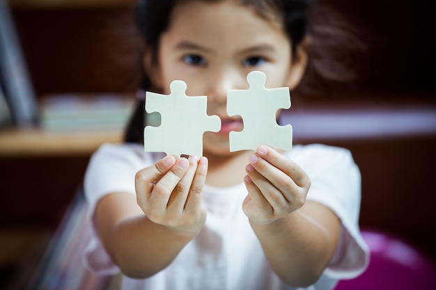 Cute asian little girl making a puzzle