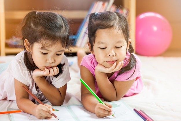 Cute asian little girls draw with their crayons. Vintage color tone