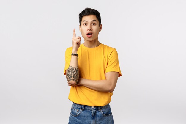 Cute asian man in yellow t-shirt having an idea