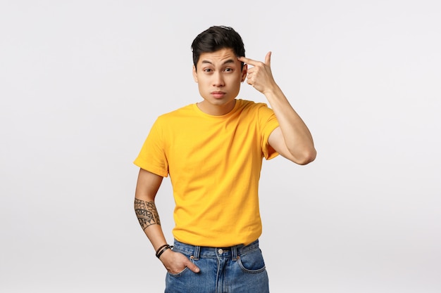 Cute asian man in yellow t-shirt pointing his head