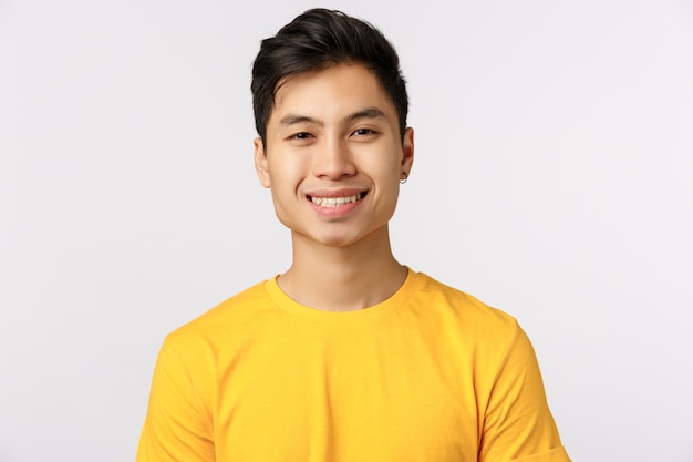 Cute asian man in yellow t-shirt smiling