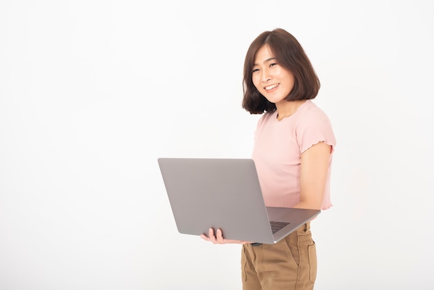 Cute Asian teen woman is working with computer on white wall