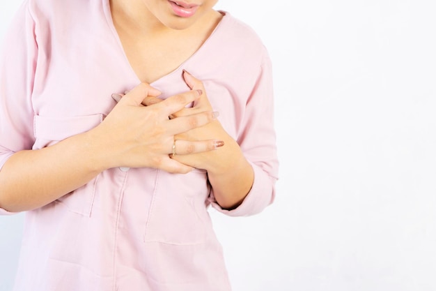 귀여운 아시아 여성이 손으로 가슴을 잡고 질병의 징후를 보이는 급성 심장병으로 고통 받고 있습니다. 회색 고립 된 배경