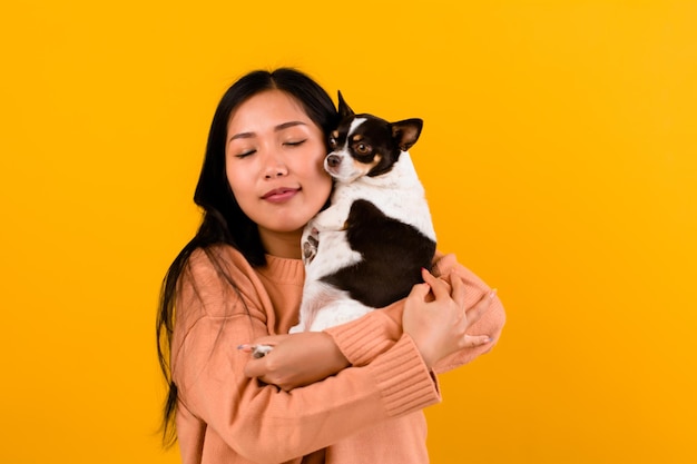 Cute Asian woman with his chihuahua chihuahua dog lover The happiness of a girl who loves his dog The love of people and cute dogs photo shoot in orange studio