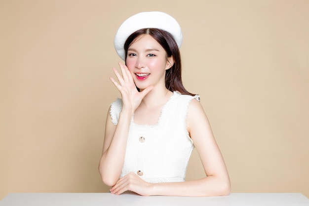 Cute asian woman with perfect skin and screaming announcement\
pretty girl model wearing white beret and natural makeup on beige\
background cosmetology beauty and spa wellness plastic surgery