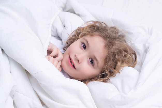 Cute awaking child in bed bedtime childhood and growth kids concept closeup indoor portrait