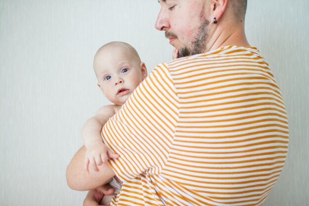 Cute baby on the arms of his big strong dad.