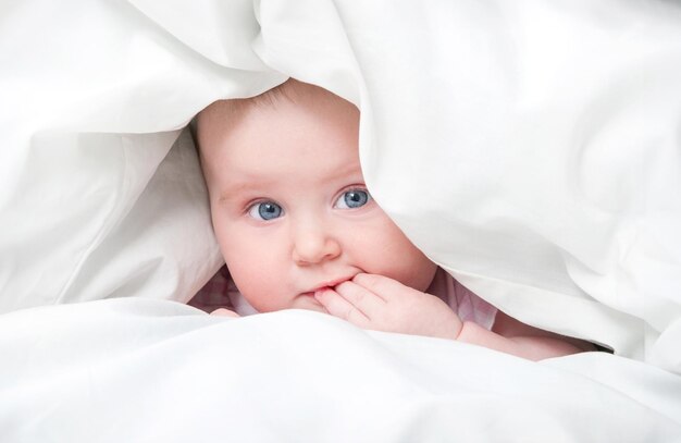 Photo cute baby under a blanket in bed