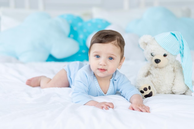 Cute baby boy on the bed to sleep with teddy bear baby room interior healthy happy little baby