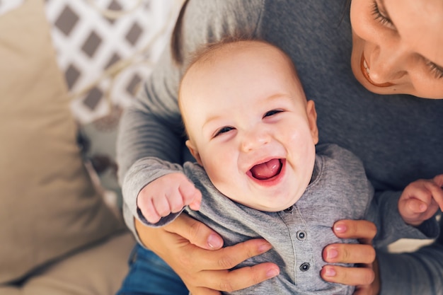 Cute baby boy on blue laughing with mother