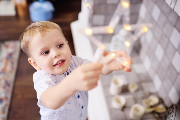 Cute baby boy dresses up a christmas tree and smiles