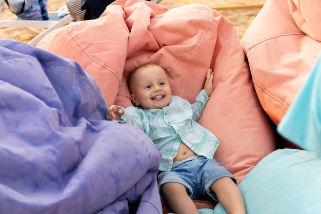 A cute baby boy lies on the bean bag  multicolored chairs