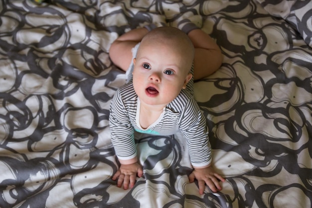Cute baby boy lying on bed at home