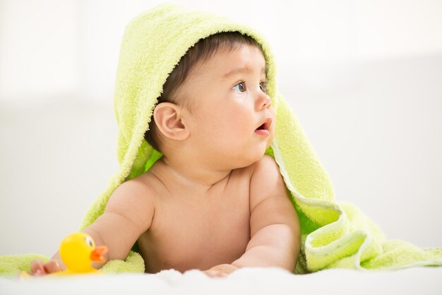 Cute baby boy lying under a towel