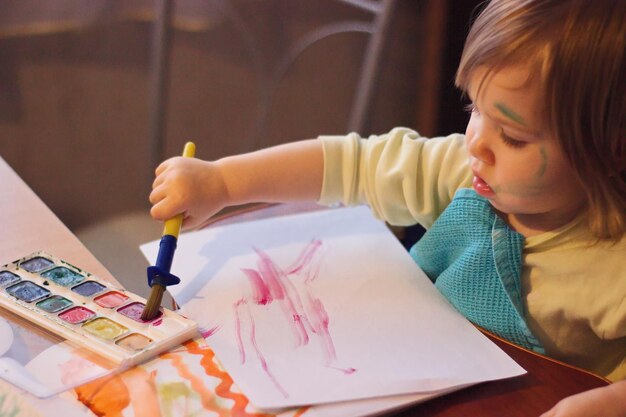 Photo cute baby boy painting on table at home