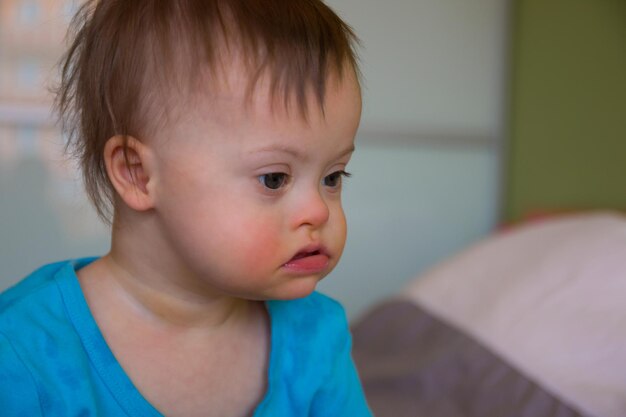 Cute baby boy sitting on bed at home