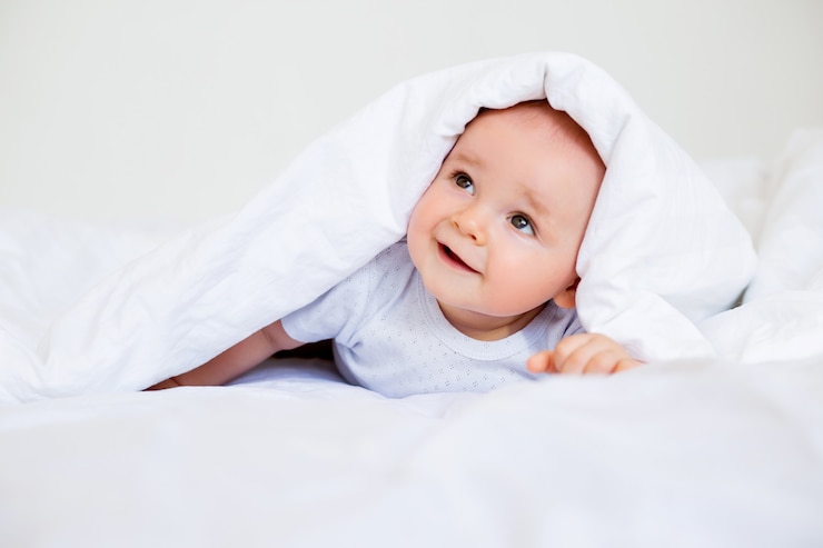 Photo cute baby boy smiling lies in the bed of the house. bedding for children
