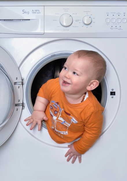 Cute baby boy standing in washing machine