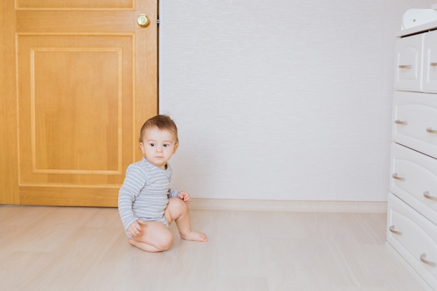 Cute baby boy toddler sitting on the floor in bedroom