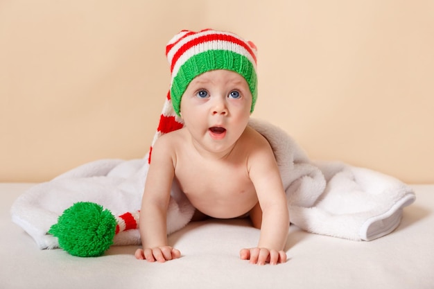 Neonato sveglio che porta il ritratto rosso del cappello di babbo natale di un bambino gioioso