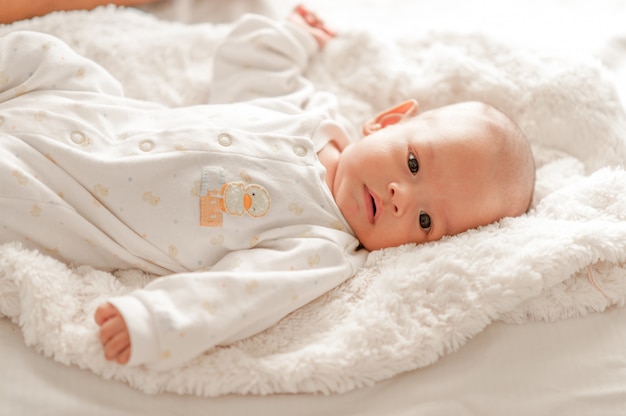 Cute baby boy in a white light bedroom Newborn baby is cute. In bedding for children born - images