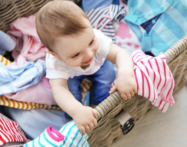 Cute baby boy in wicker basket with clothes