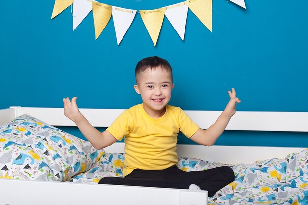 Cute baby boy with Down syndrome on the bed in home bedroom