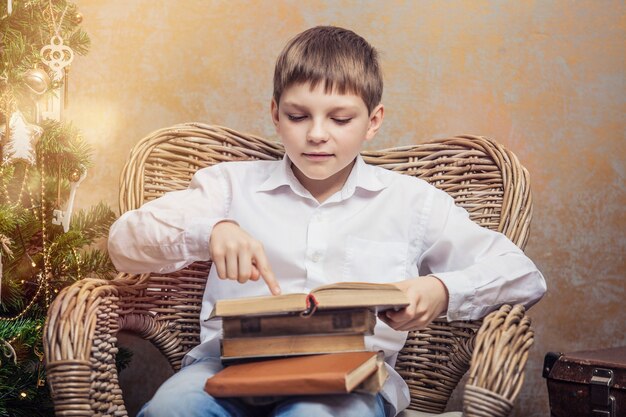 Cute baby in a chair reading a book in a Christmas retro interior