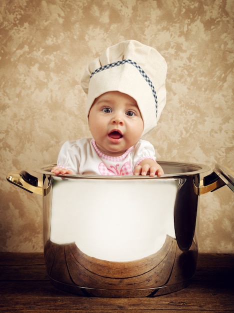 Cute baby chef in a huge cauldron