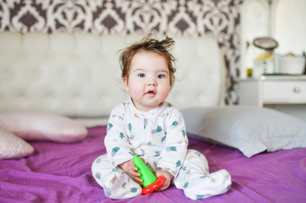 Cute baby, close up. Portrait of a crawling baby on the bed in her room.