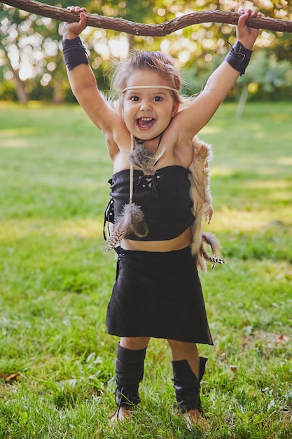 Cute baby dressed in the clothes of primitive people with combat staff