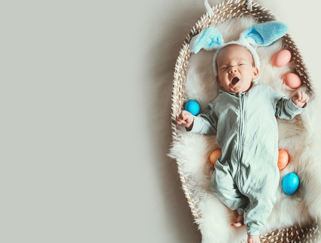 Cute baby Easter bunny Little baby boy with bunny ears and Easter eggs in wicker basket