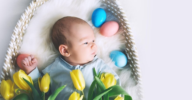 Cute baby Easter bunny Little baby boy with bunny ears and Easter eggs in wicker basket