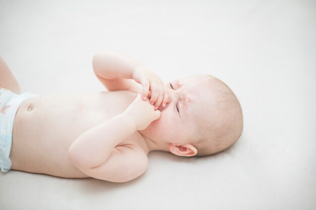 Cute baby girl crying on the bed