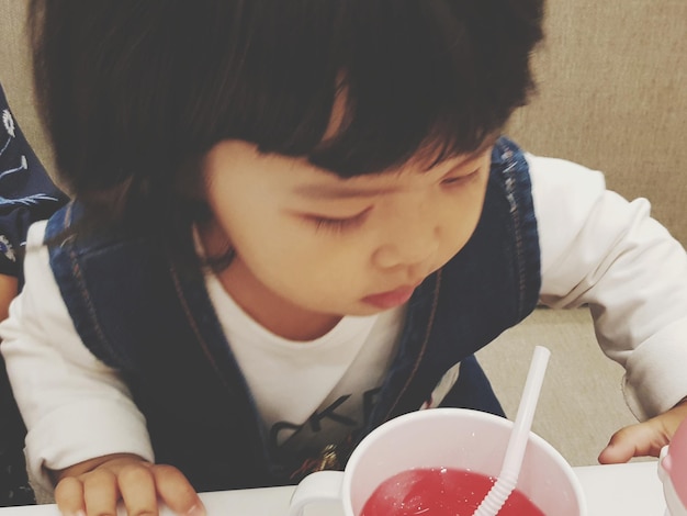 Cute baby girl drinking juice at restaurant