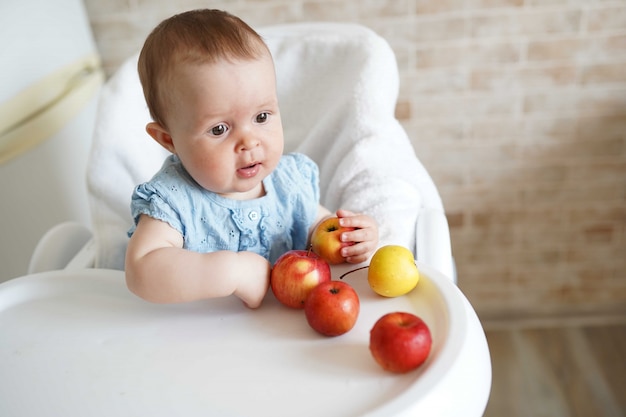Cute baby girl eating apple in the kitchen.