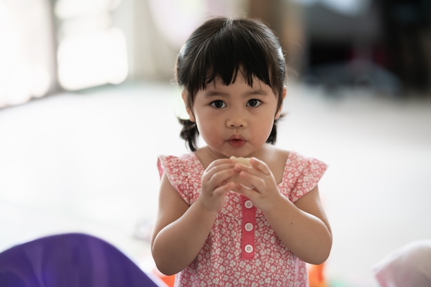 Cute baby girl eating cookies in the house