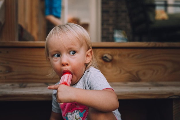 cute baby girl eating flavored ice cream