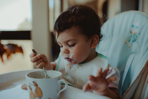 Photo cute baby girl eating food at home