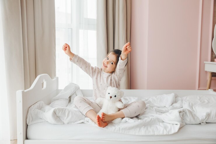 Photo a cute baby girl enjoys a sunny morning good morning at home a baby girl wakes up on a bed with a teddy bear
