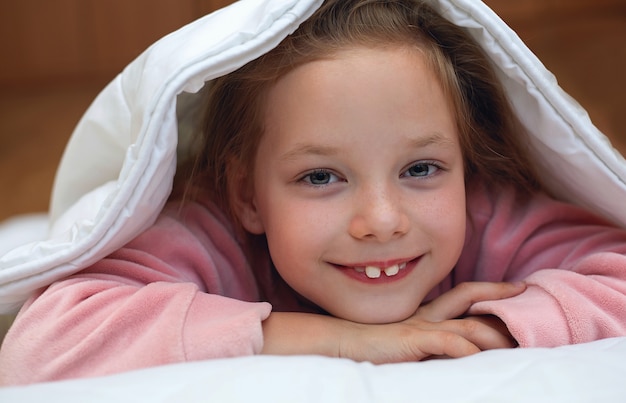 Photo cute baby girl hiding under the blanket