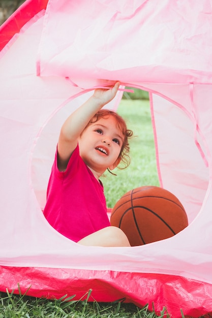 Foto piccola bambina carina con la pallacanestro in tenda